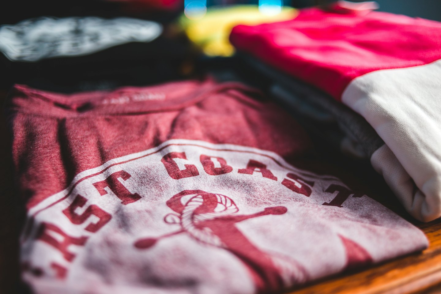 Rotes und weißes East Coast T-Shirt auf Holz gefaltet.